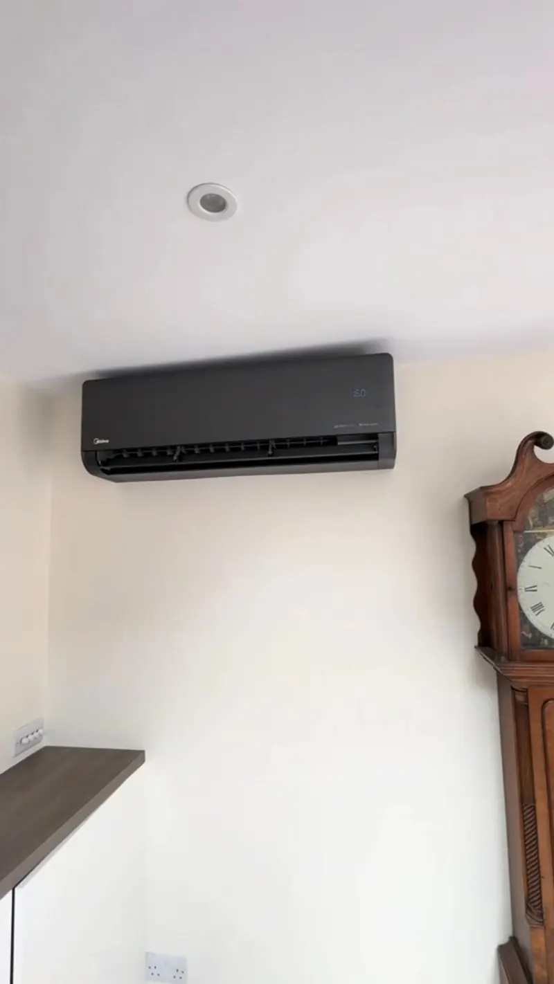 Matte black indoor air conditioning unit on a white wall in a period room