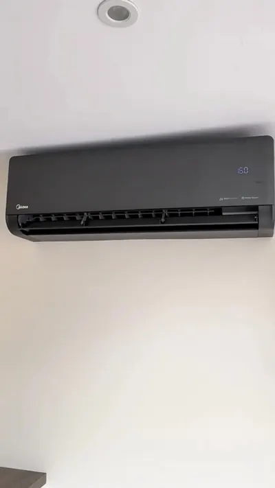 White wall-mounted indoor air conditioning unit showing the set temperature on its display